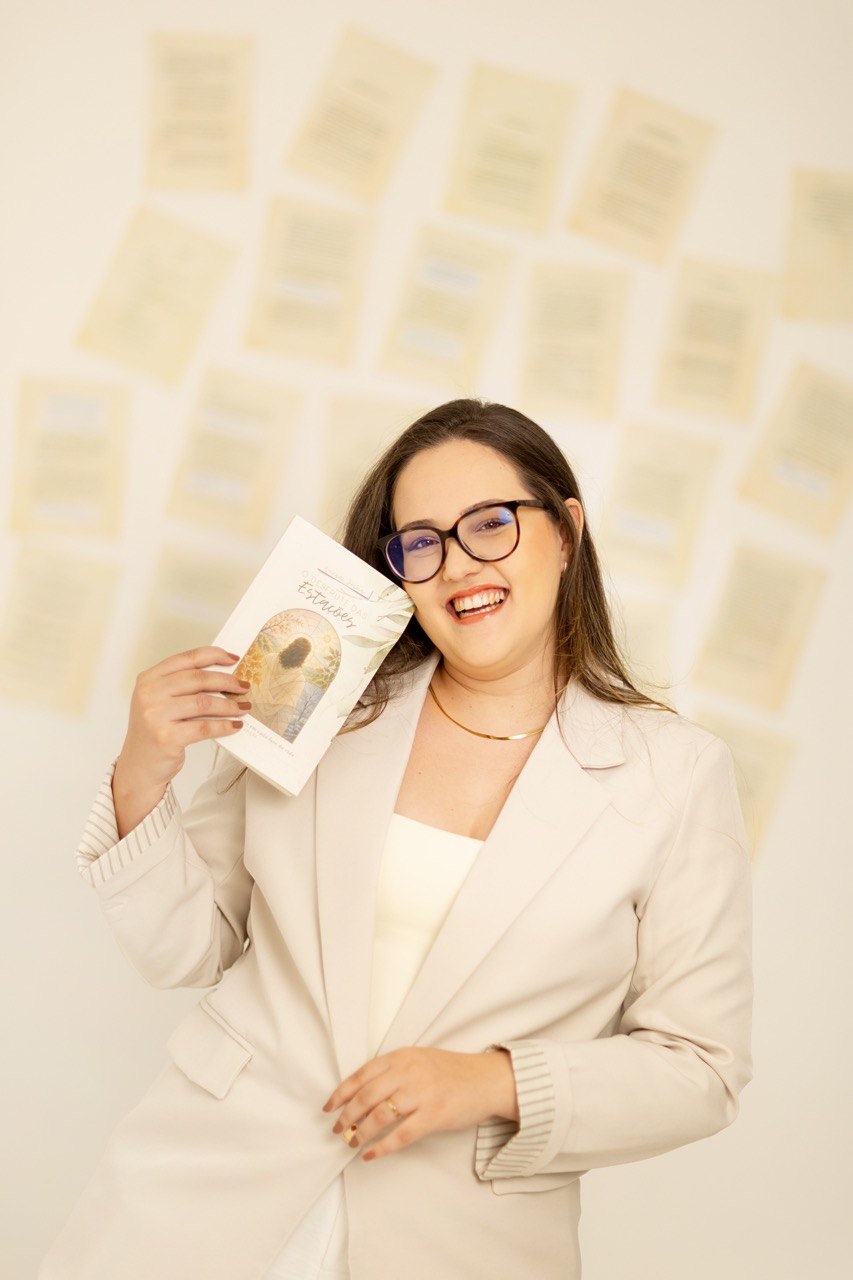 Luísa Costa Jesus sorrindo, segurando o livro O Desfrute das Estações.